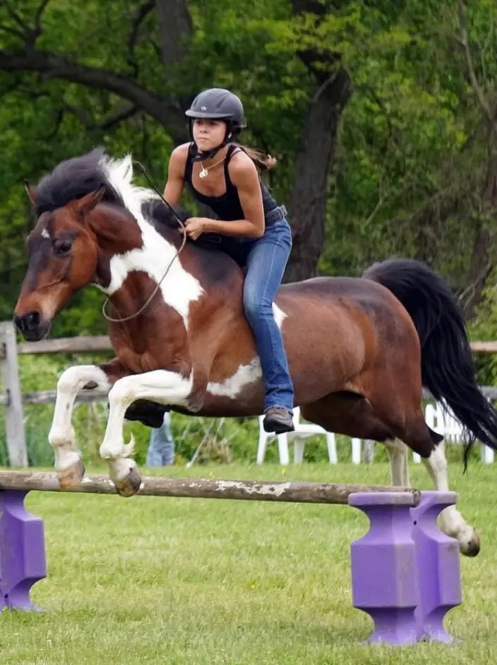 A woman riding on the back of a brown and white horse.