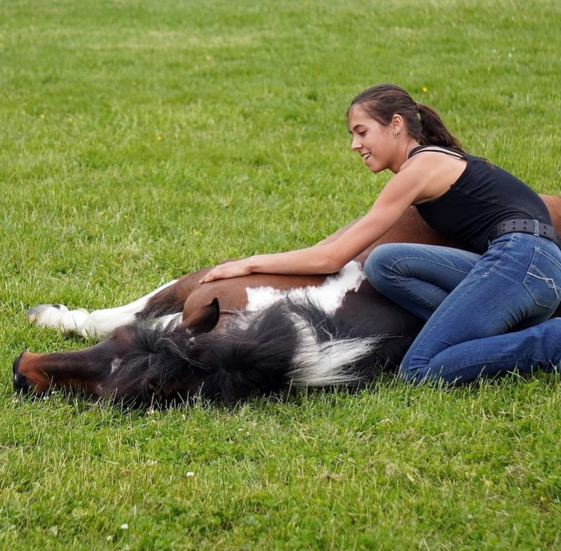 A woman sitting on the grass with her dog.